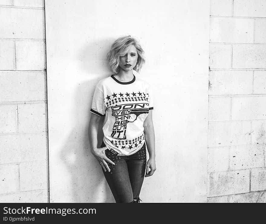 Woman in Crew-neck T-shirt and Pants Leaning on Wall