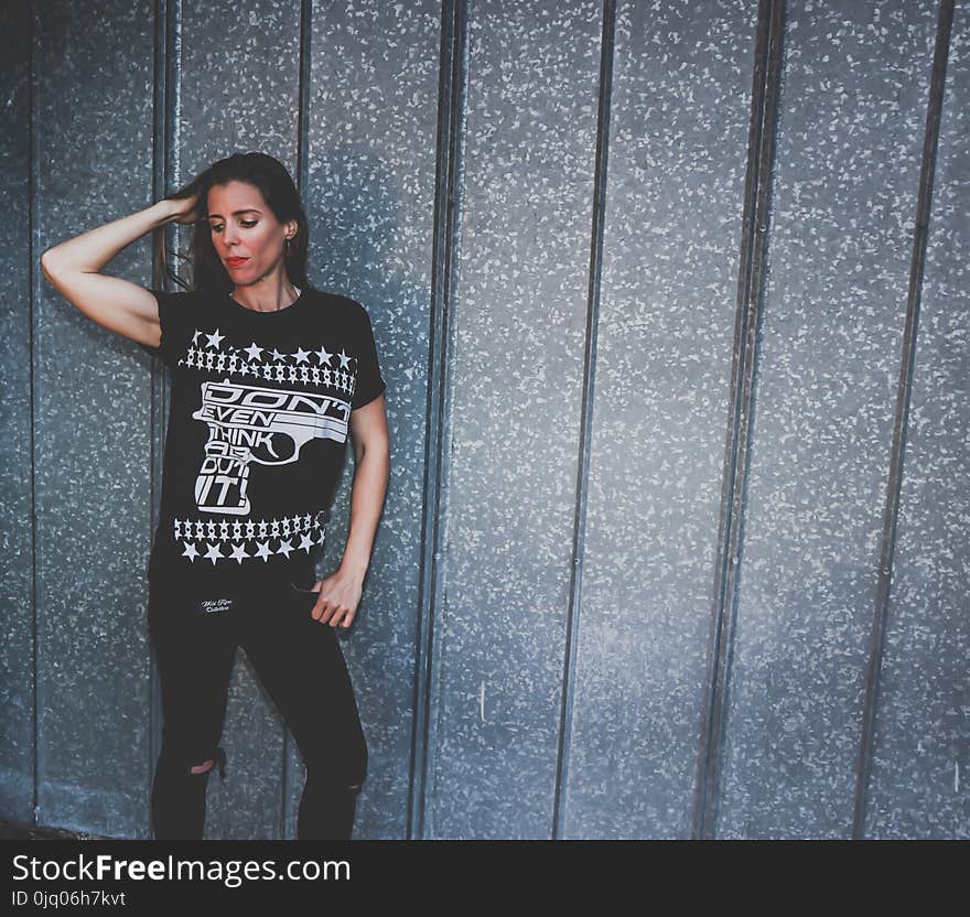 Woman Leaning on Gray Wall While Holding Hair