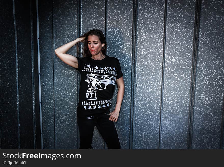 Woman Wearing Black Shirt and Pants Near Gray Wall