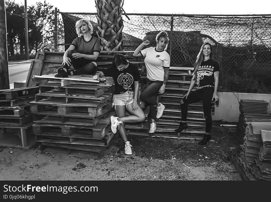 Grayscale Photo of Four Women on Wooden Pallets