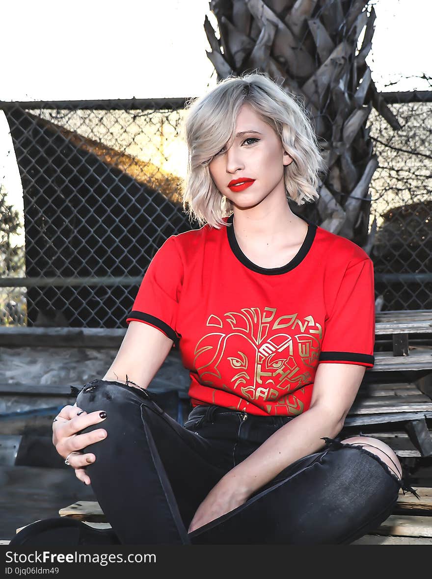 Woman in Red Crew-neck Shirt Sitting in Bench