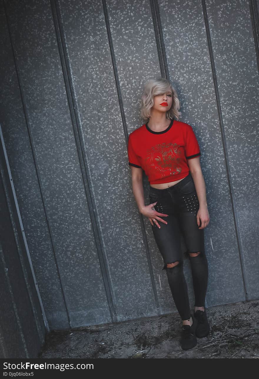 Woman Wearing Red Shirt Leaning on Gray Wall