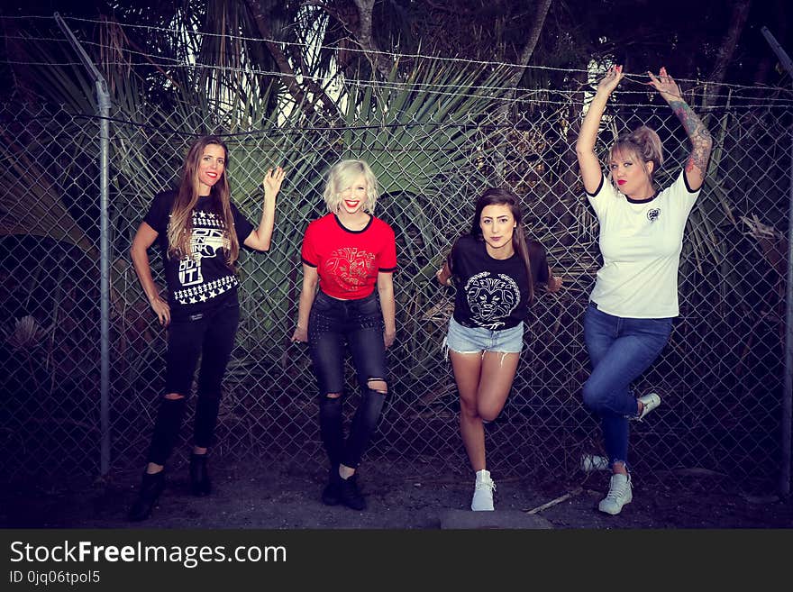 Four Woman Leaning on Chain Link Fence