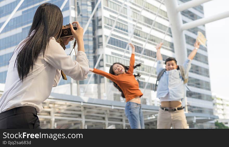 Business women hold camera to shoot the traveler couple people at urban city and modern building. Honeymoon trip, holiday vacation travel concept. Business women hold camera to shoot the traveler couple people at urban city and modern building. Honeymoon trip, holiday vacation travel concept.