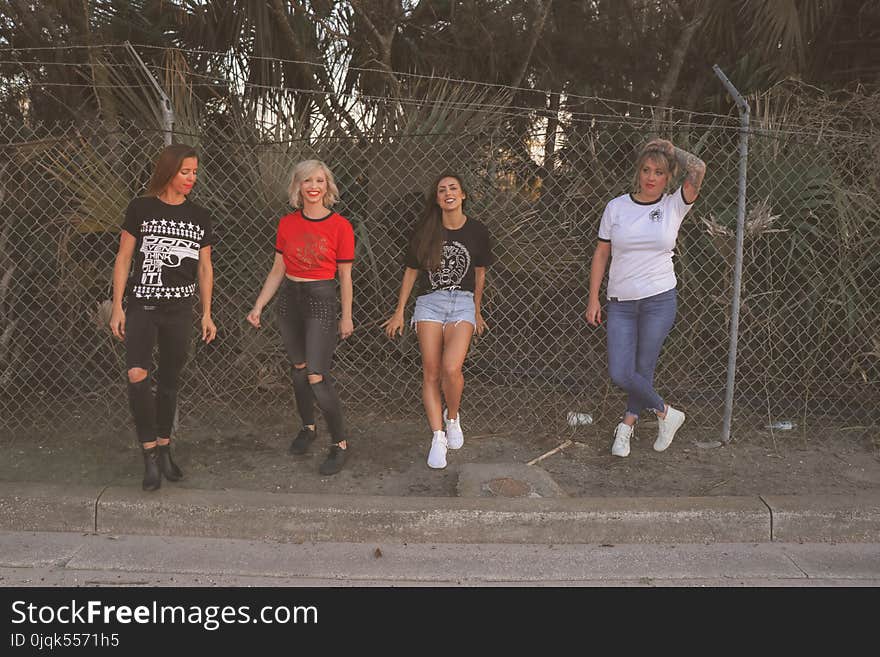 Four Women Standing Against Wire Fence