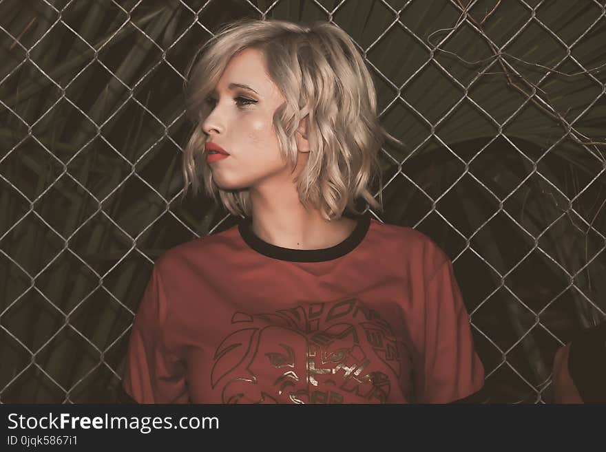 Close-Up Photography of a Woman Leaning On Chain Link Fence