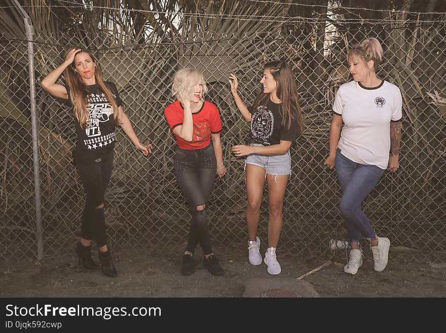 Photo of Four Women Leaning on Chain-link Fence