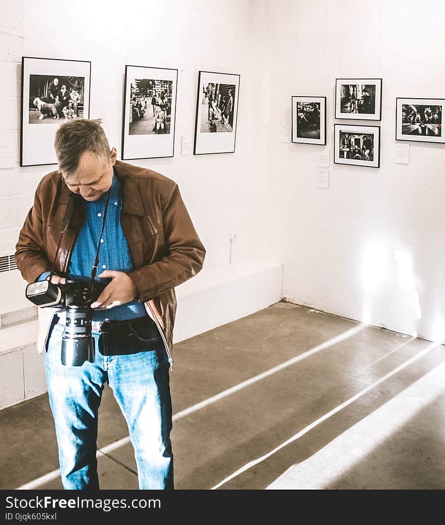 Man in Brown Jacket, Blue Denim Jeans and Blue Dress Shirt Holding Dslr Camera