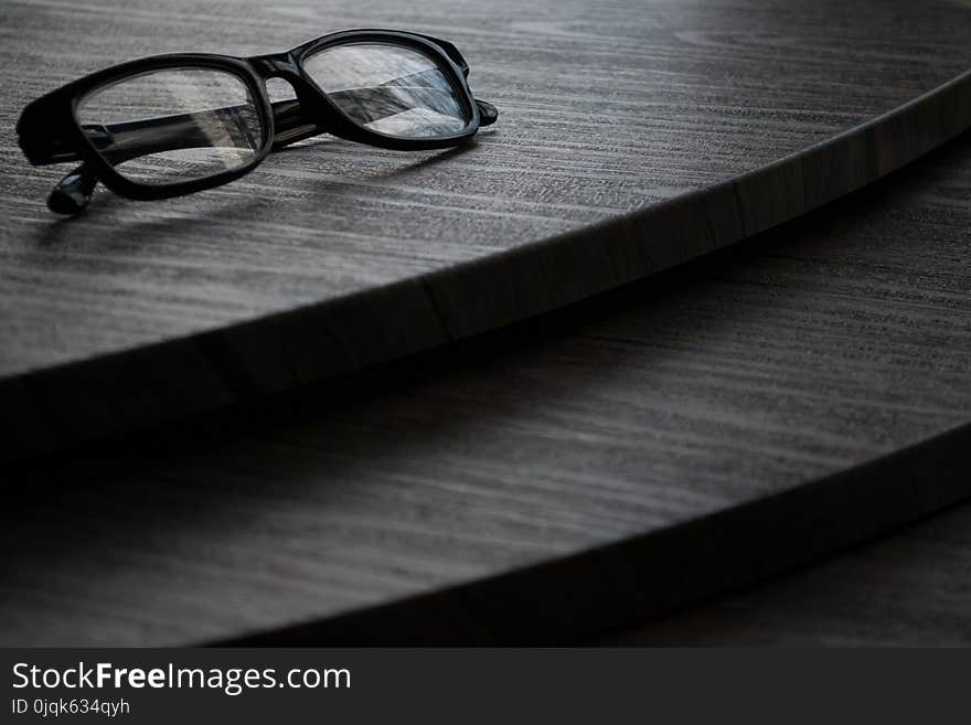 Black Framed Eyeglasses on Brown Surface