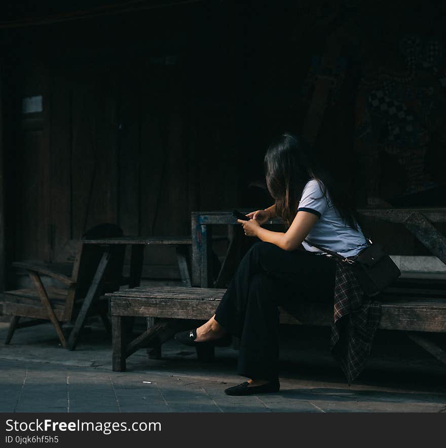 Woman Wearing White Crew-neck Shirt Sitting on Brown Wooden Bench