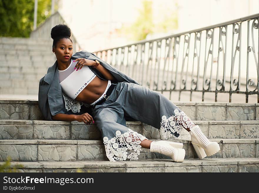 Woman Wearing White Sports Bra and Gray Pants Laying on Stairway