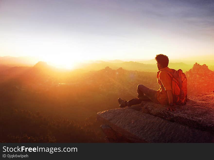 Man Sitting on Edge Facing Sunset