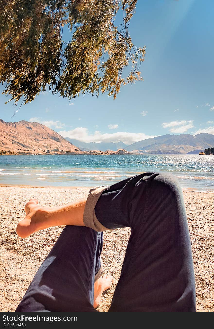 Person Wearing Blue Jeans Laying on Beach