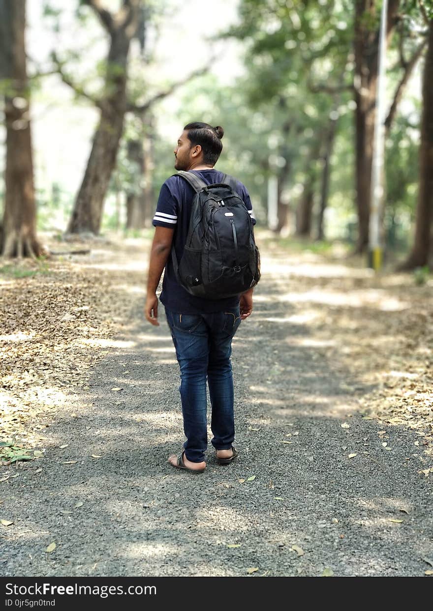 Man in Black and White T-shirt and Blue Denim Jeans Carrying Backpack