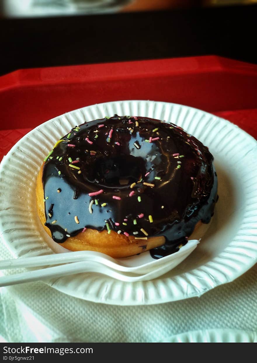 Chocolate Donut Above Round Paper Plate and Plastic Spoon and Fork