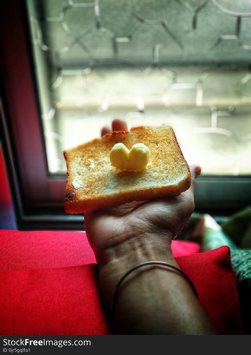 Person Holding Toast With Butter on Top