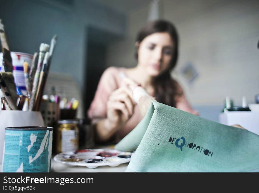 Woman Holding Paper Near Paint Brushes