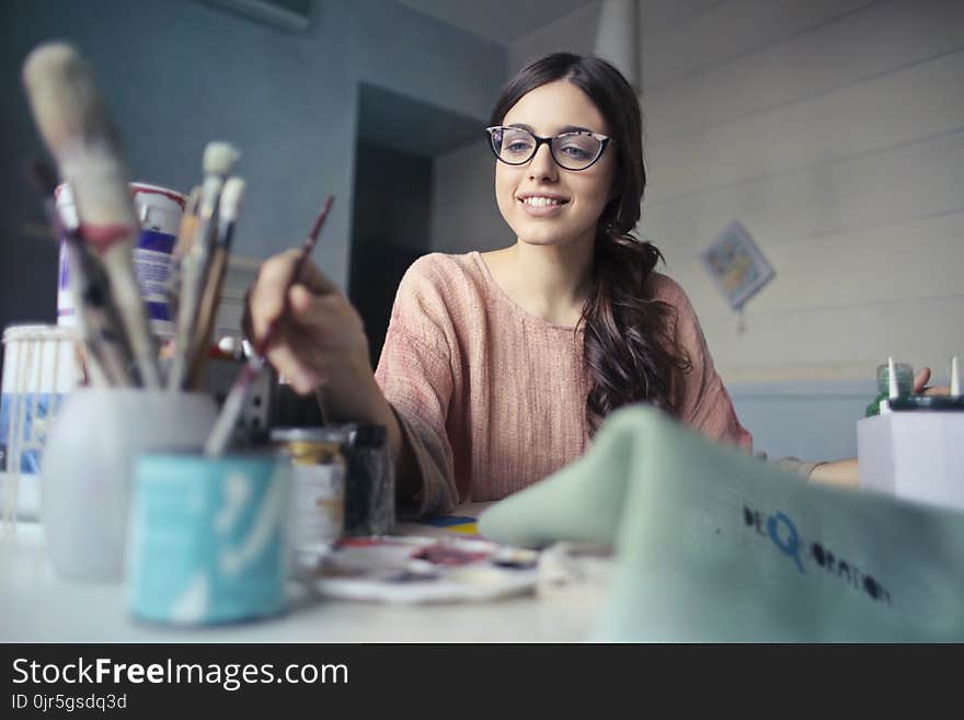 Woman in Brown Long-sleeved Shirt Wearing Eyeglasses Holding Paint Brush