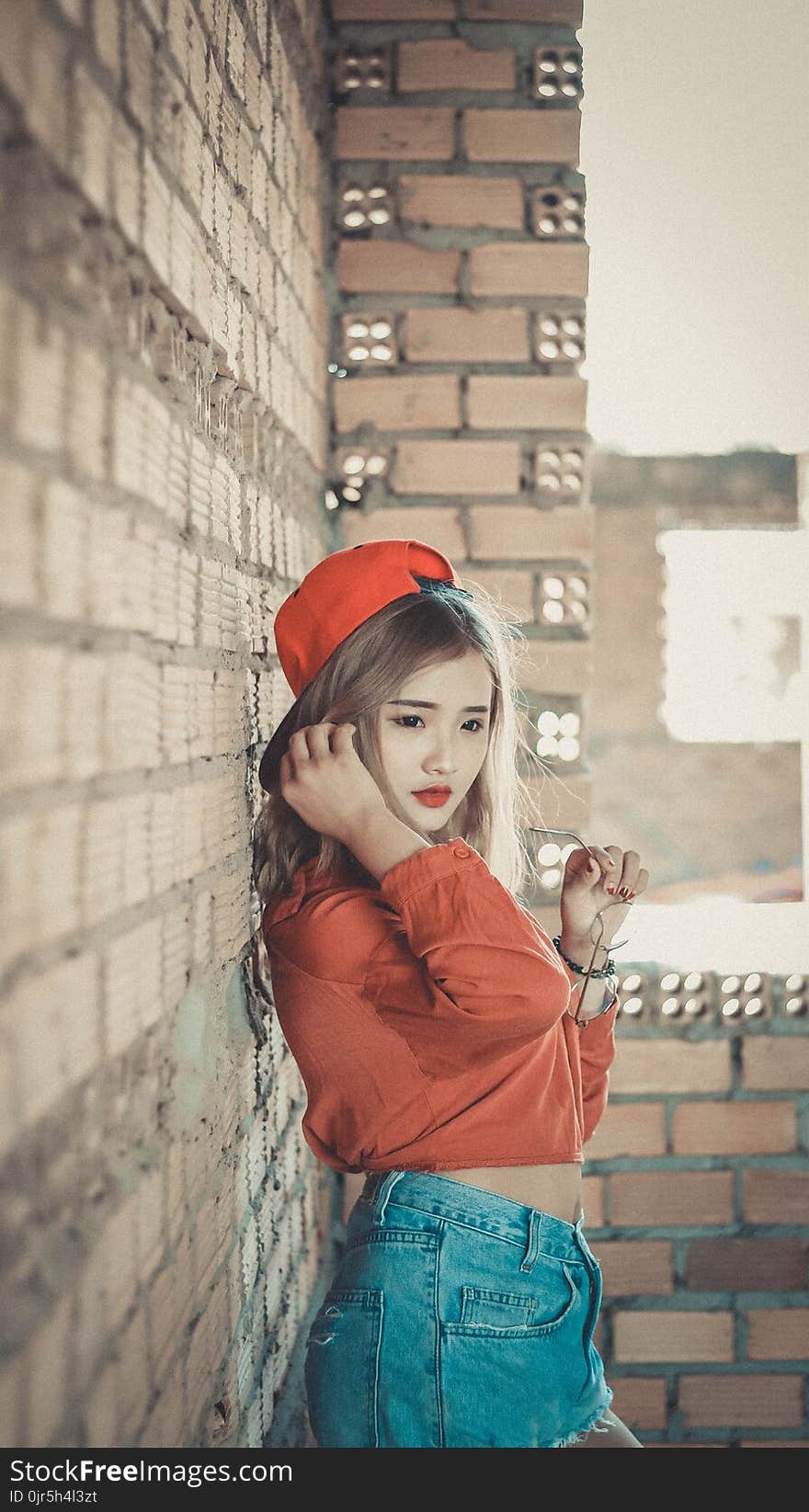 Girl in Orange Top Near Brown Concrete Brick