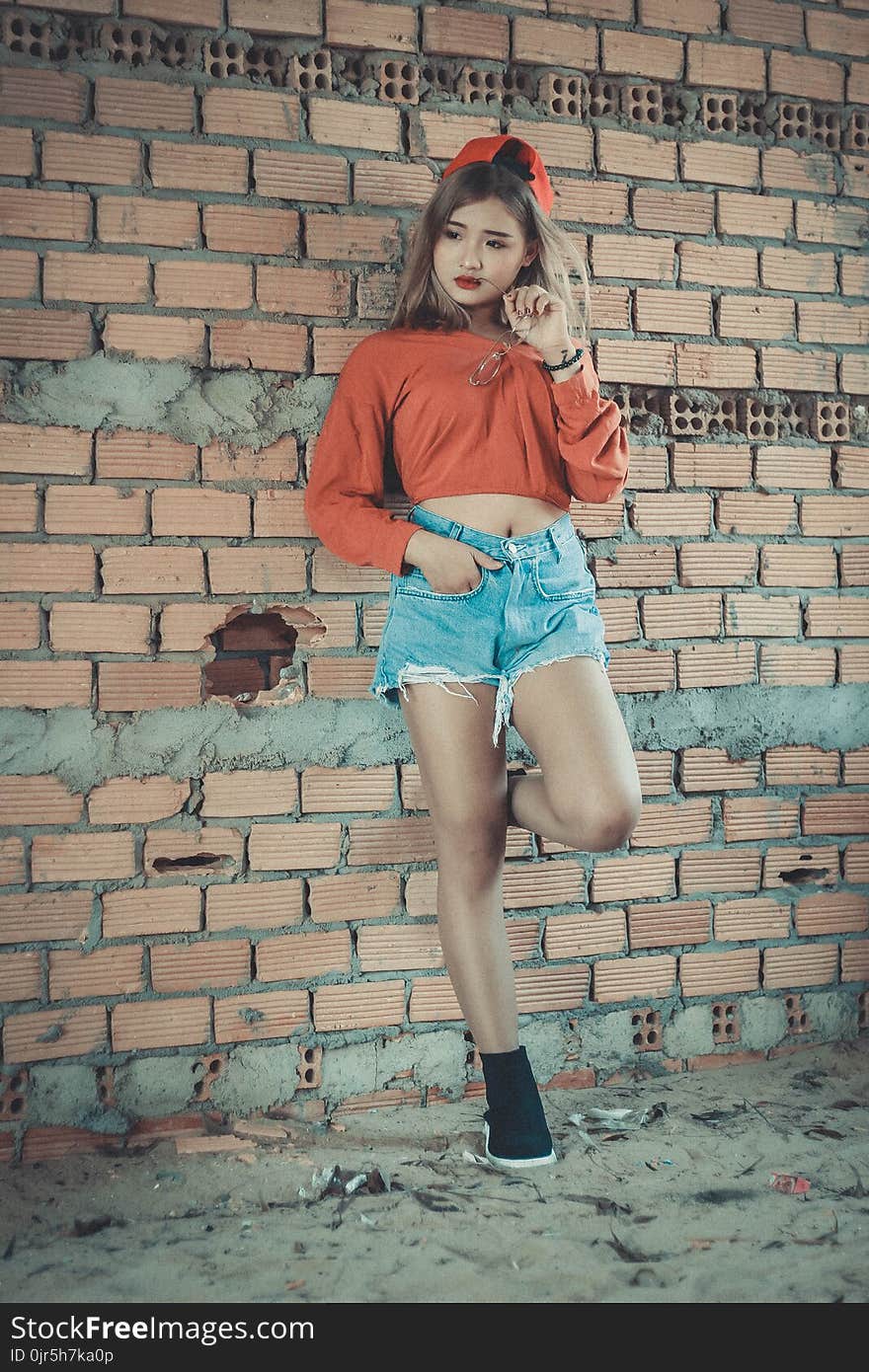 Photo of Woman Wearing Orange Crop-top Near Brown Concrete Brick Wall