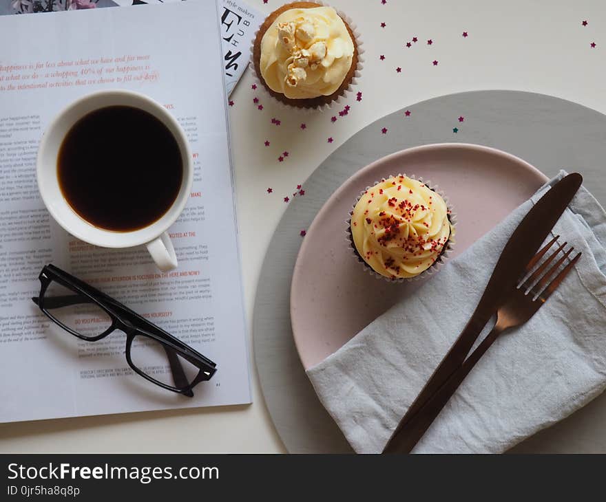 Top-view Photograph of Two Cupcakes, Cup, and Eyeglasses