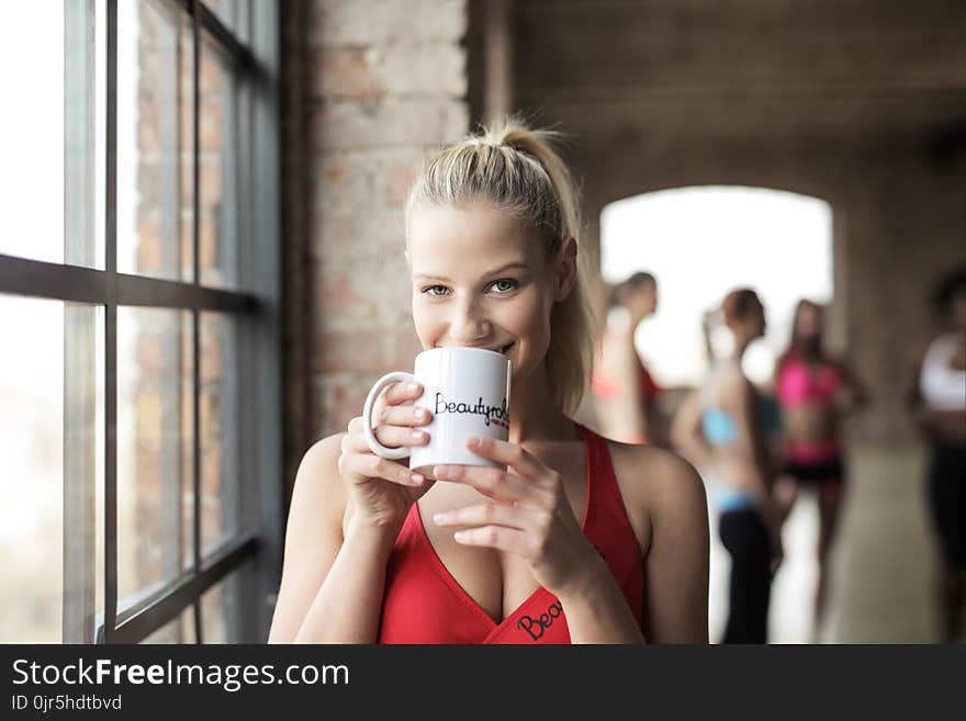 Woman in Red Scoop-neck Tank Top Holding White Mug