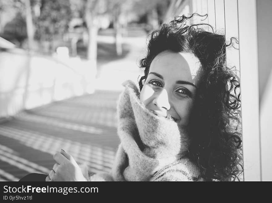 Grayscale Photo of Woman Leaning on White Pole