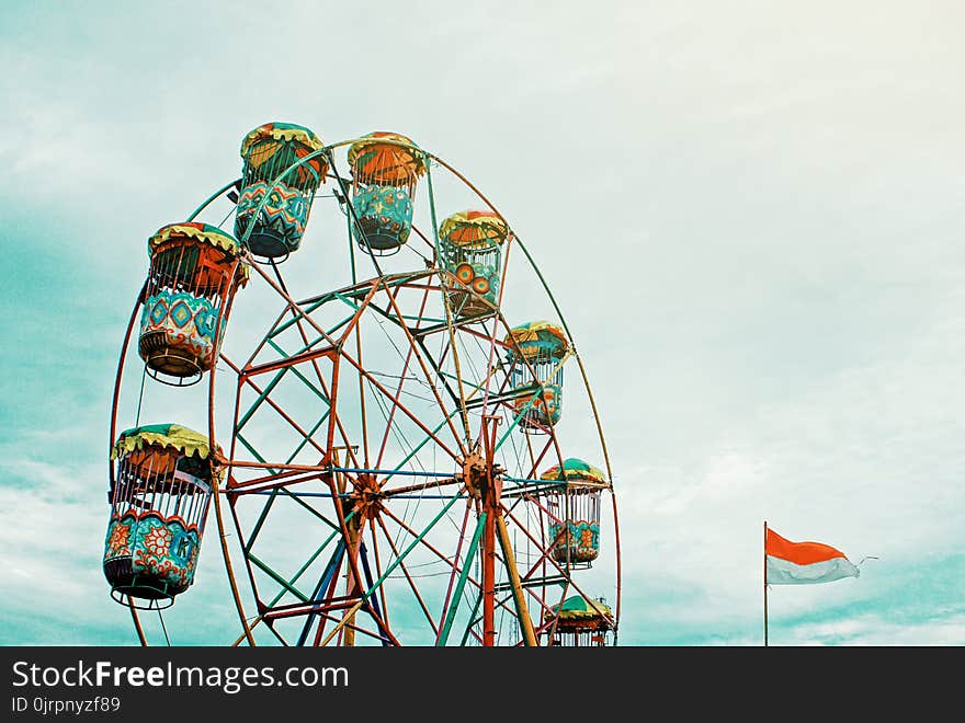 Photography of Orange Ferris Wheel Beside White and Orange Flag