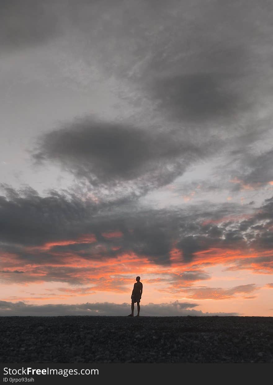 Silhouette of Man Standing Underneath Gray Sky