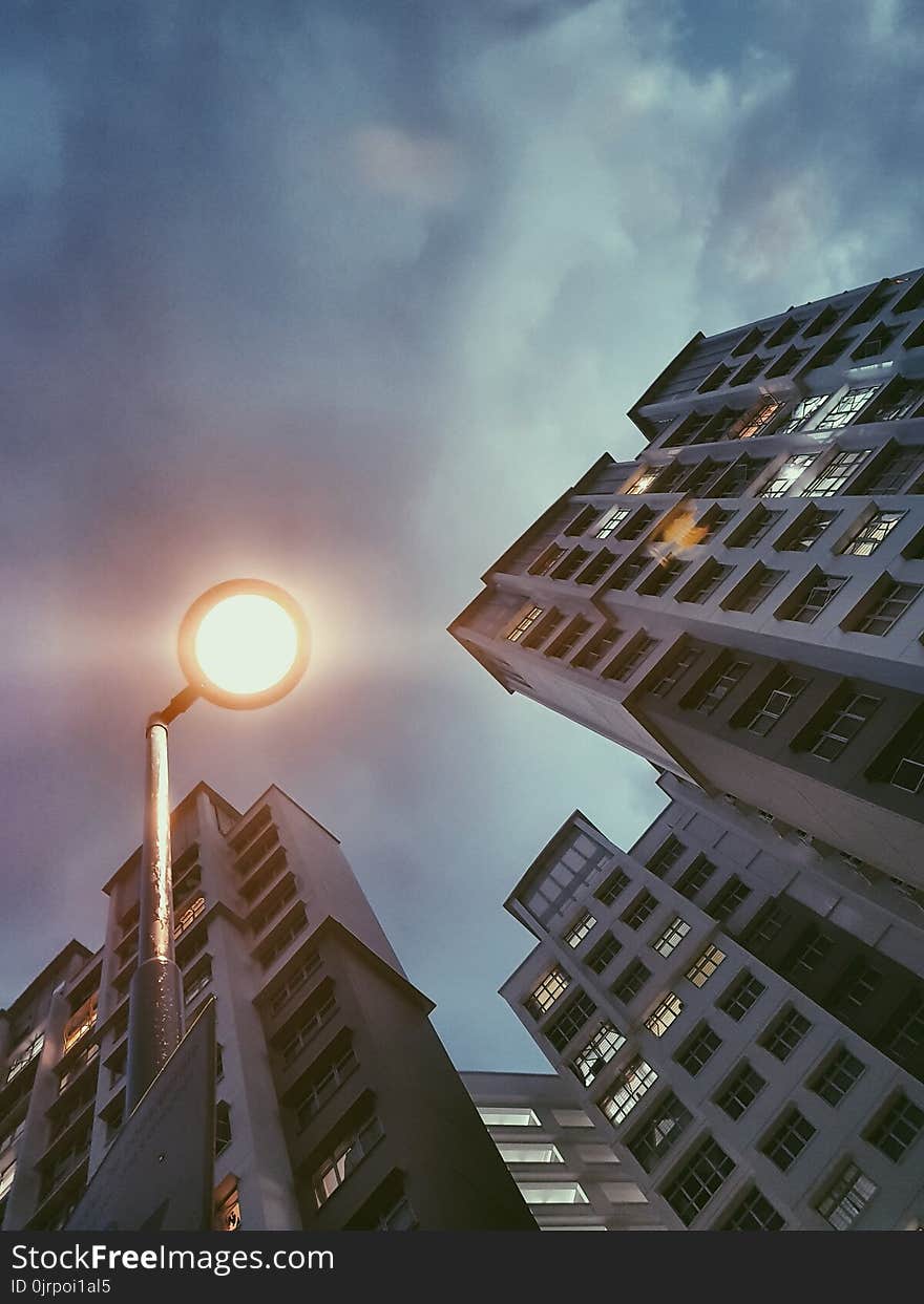 Low Angle Photography of Lamp Post Beside Building Under Cloudy Sky