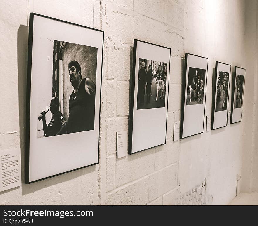 Five Assorted Grayscale Posters on White Concrete Wall