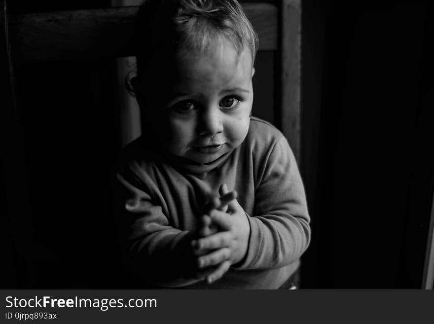 Grayscale Photo of Baby Sitting on Chair