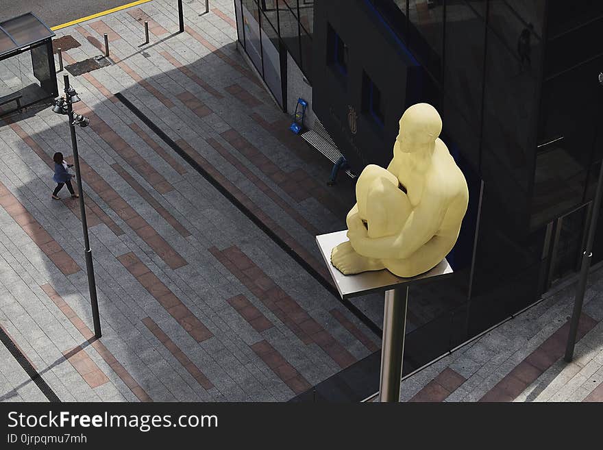 Sitting Man Statue Placed on Gray Metal Post