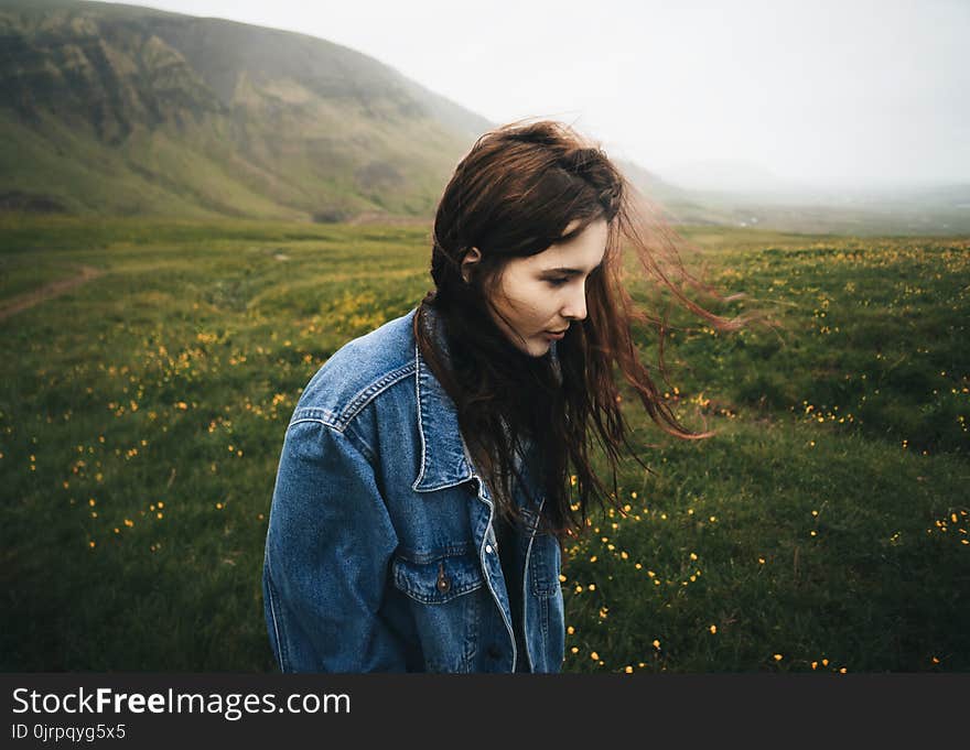 Woman Wearing Blue Denim Jacket Walking on the Green Grass Field