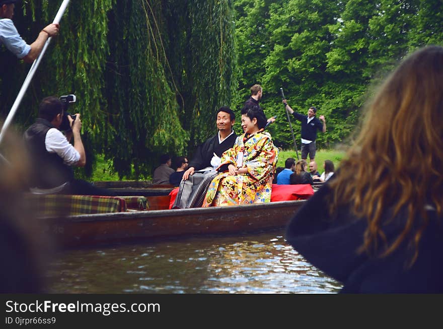 Man and Woman Sitting on Brown Canoe