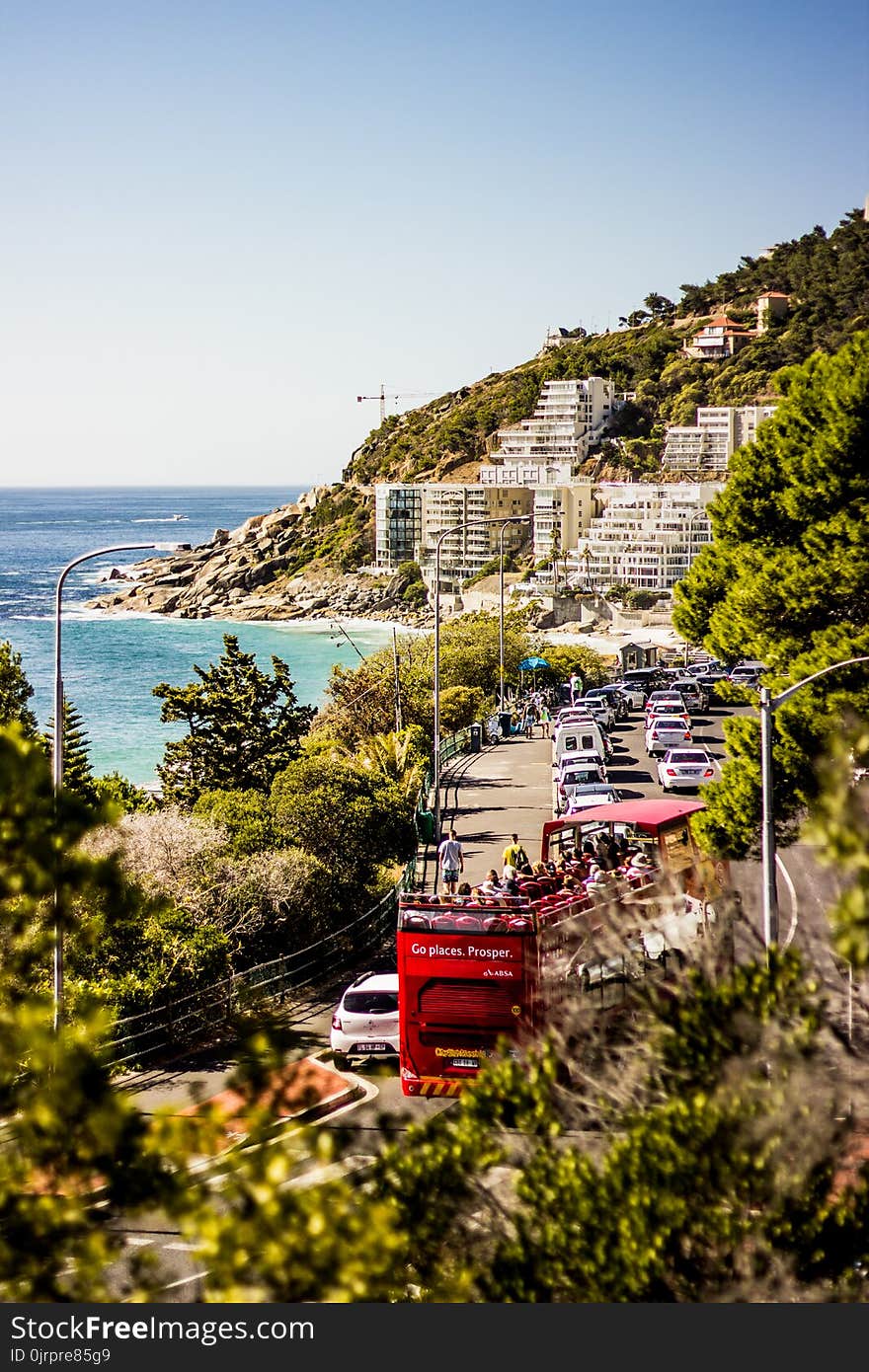 Cars on Road Near Blue Sea and Green Covered Mountains