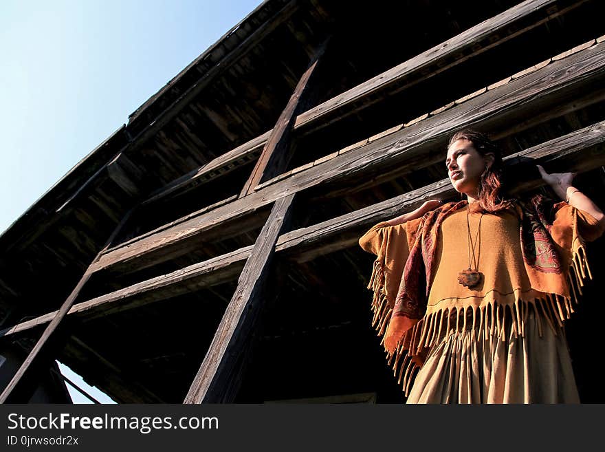 A beautiful girl stands under the roof of a house