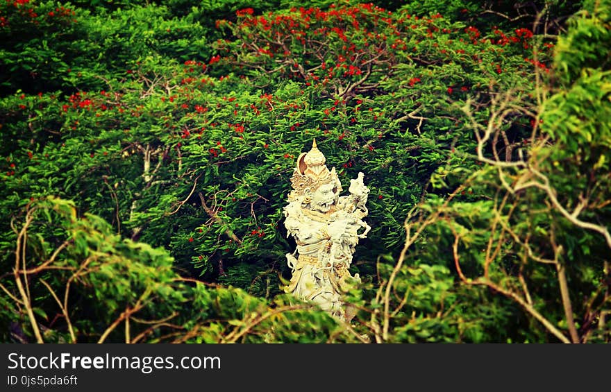 Beige Hindu Statue Surrounded by Trees at Daytime