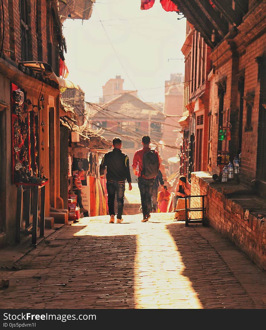 Two Man Walking Beside Brick Houses