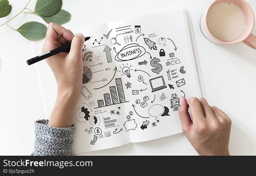 Person Holding Black Pen and Book Near Pink Ceramic Mug