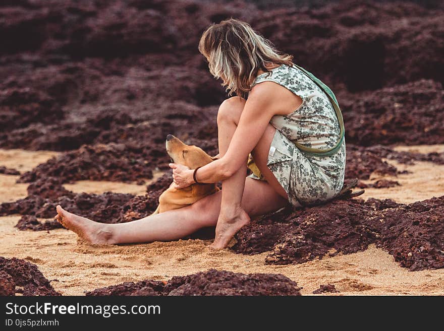 Woman With Green Floral Sleeveless Mini Dress Sitting on Brown Sand Close-up Photography