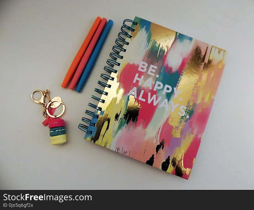 Be Happy Always Spring Notebook Beside Three Assorted-color Pens