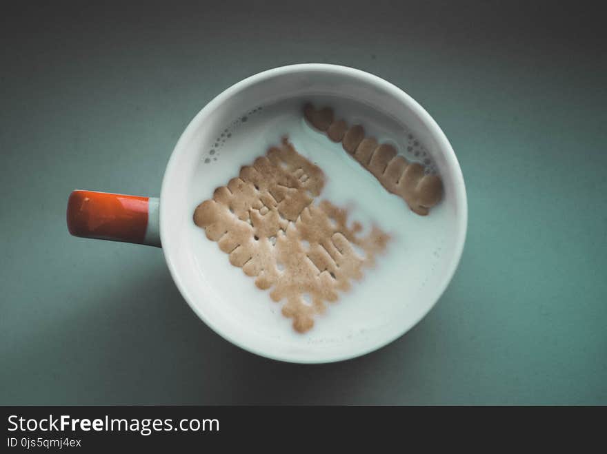 White Mug Filled White With Milk and Brown Biscuit