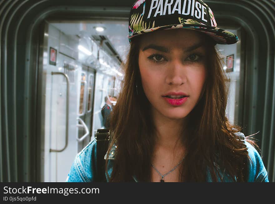 Woman in Blue Top Wearing Black and White Cap With Paradise Text-printed