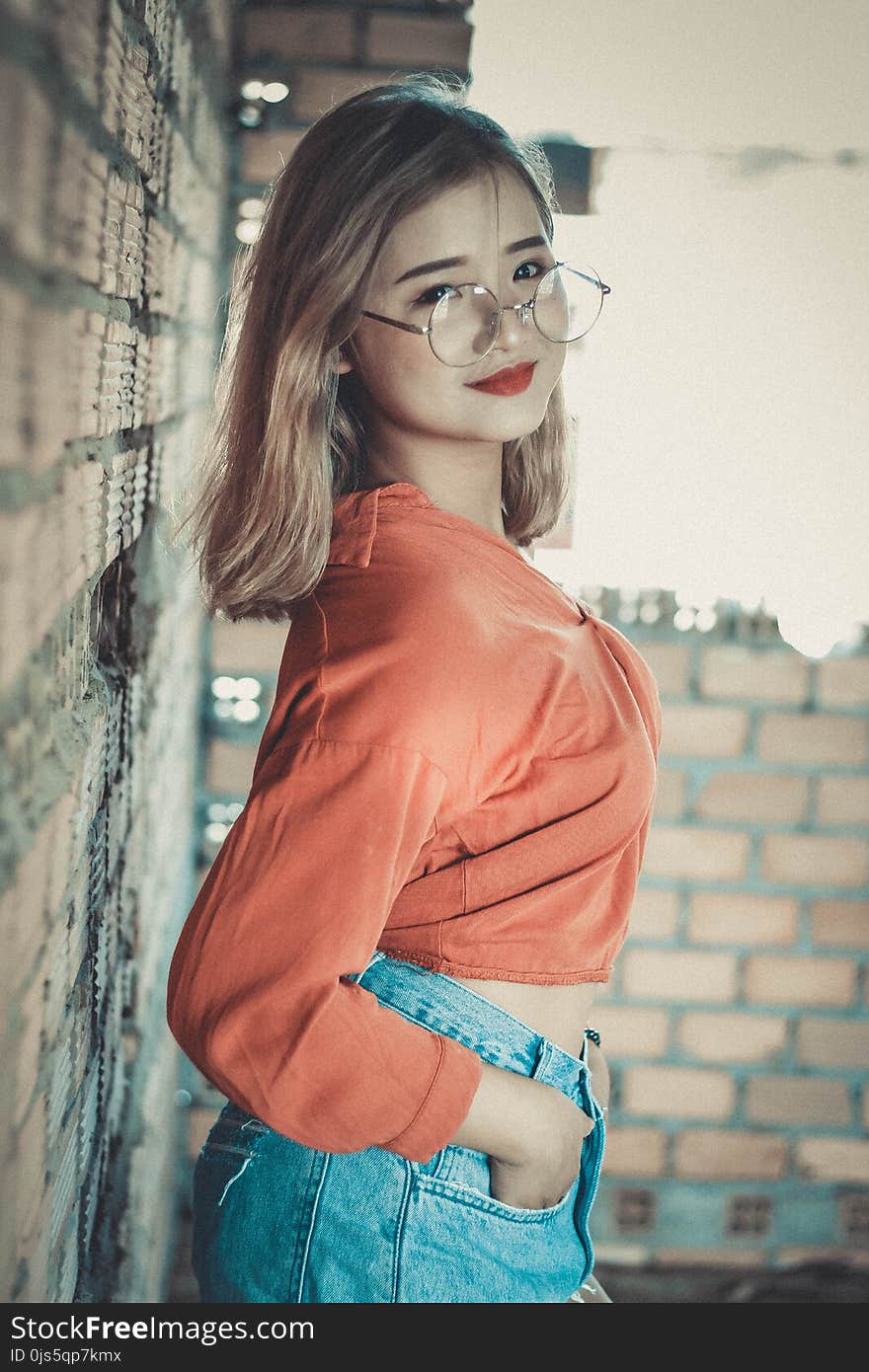 Blonde Haired Woman in Orange Long-sleeved Crop Top Wearing Round Gray Eyeglasses