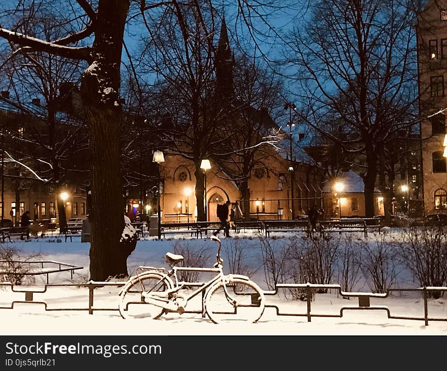 Snow Covered Bike Near Fence during Nighttime