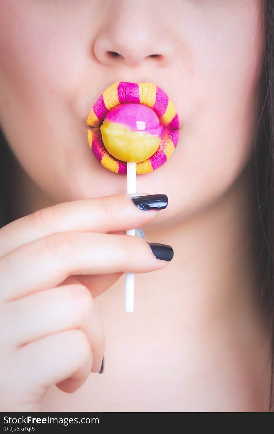 Woman Eating Pink and Yellow Lollipop