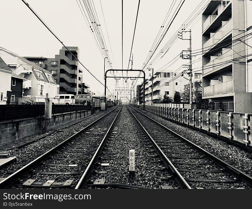 Grayscale Photography of Train Rail Between Buildings