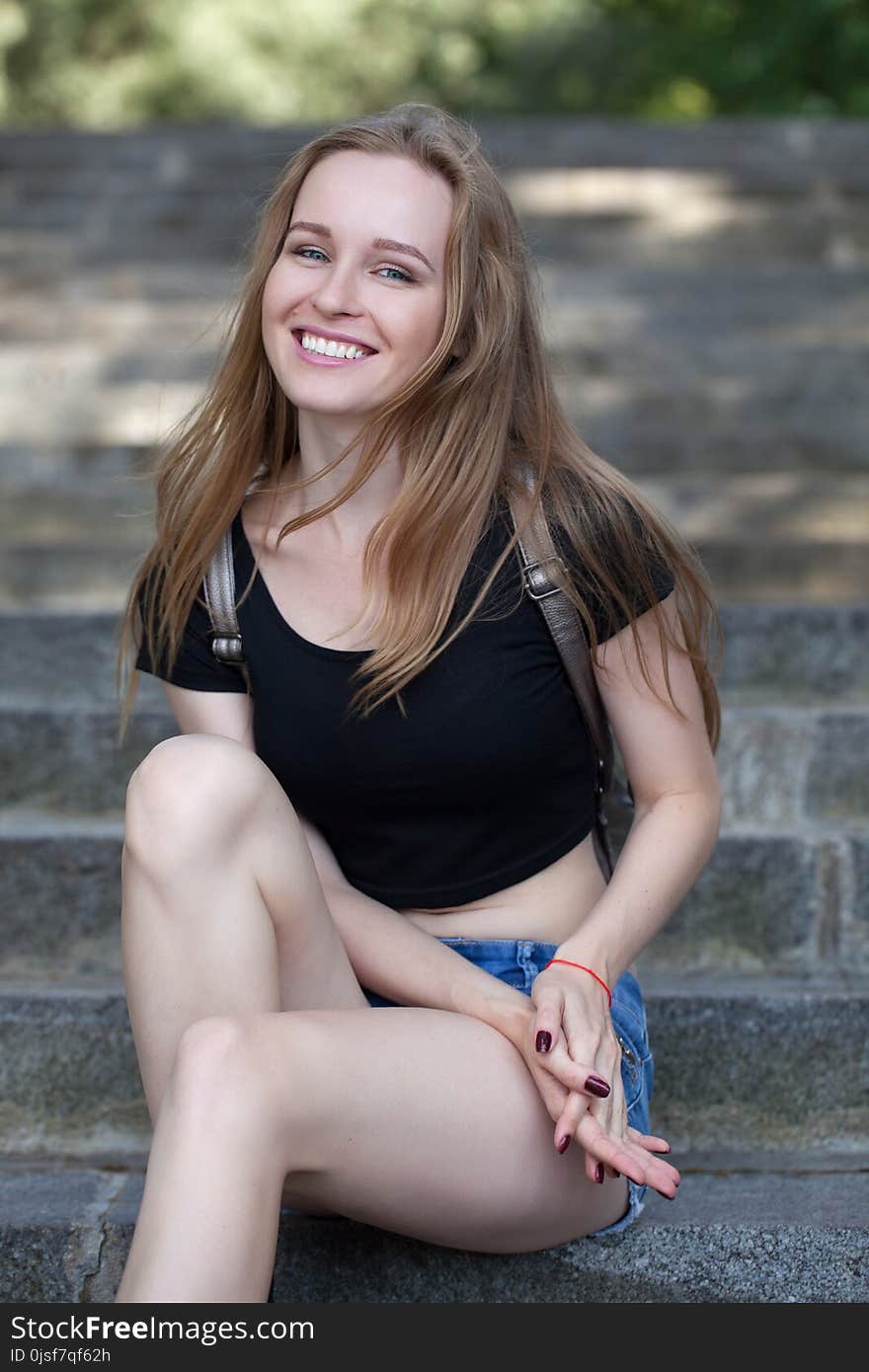 Young girl in shorts, sits on the steps. emotional portrait.