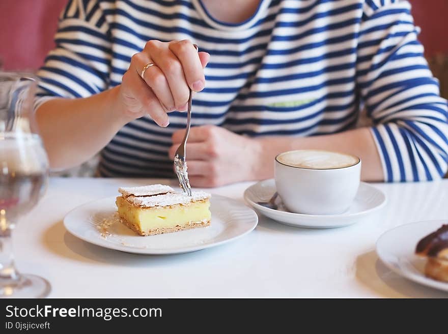 Girl in striped clothes eating fork with dessert